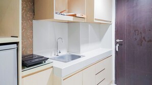 Una cocina compacta con estufa integrada, un lavamanos y armarios superiores.