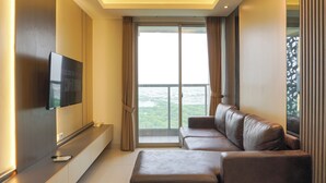 Een moderne woonkamer met een flatscreen televisie aan de wand, een bank en een groot raam met gordijnen.