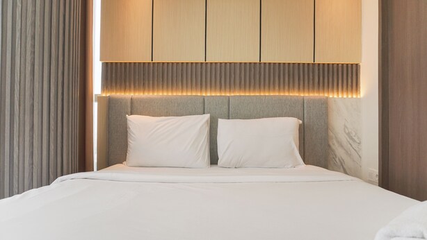 Een moderne hotelkamer met een groot bed, een hoofdeinde met ingebouwde verlichting en een marmeren accentmuur.