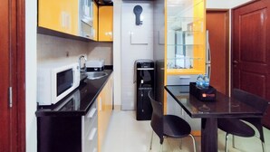 Une cuisine compacte équipée d’un four à micro-ondes, d’un évier et d’une machine à café. On y trouve également une petite table à manger avec des chaises.