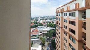 Un immeuble de grande hauteur, doté de nombreux étages et de balcons, qui offre une vue panoramique sur la ville, avec ses différents bâtiments et ses espaces verts.