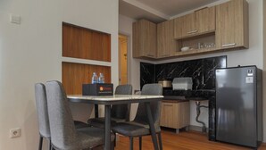 Una cocina compacta con mesa, sillas, refrigerador y armarios de madera.