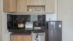 Una cocina con armarios de madera, una cubierta salpicadera de mármol negro, un refrigerador de acero inoxidable y un horno empotrado.