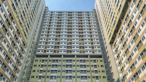 A high-rise residential building with multiple balconies and a uniform facade. - Homey And Minimalist 1Br Royal Sentul Park Apartment (Bogor)