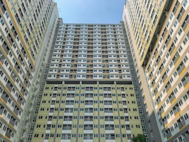 Un edificio residencial alto con varios balcones y una fachada uniforme.