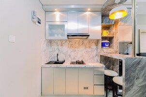 Una cocina moderna con encimera de mármol, electrodomésticos de acero inoxidable y una barra integrada con taburetes.