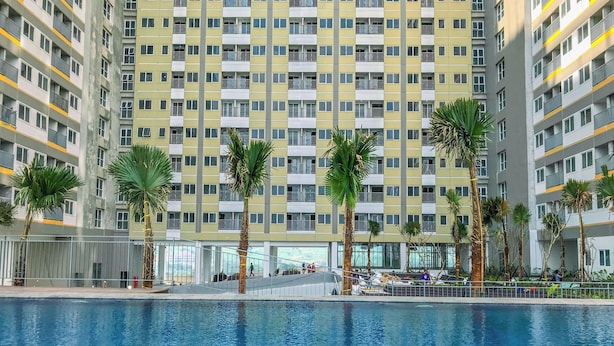 A high-rise residential building with a swimming pool in the foreground. - Homey And Minimalist 1Br Royal Sentul Park Apartment (Bogor)