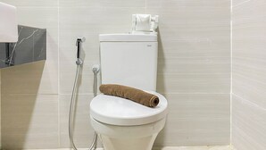 Een wit toilet met een handdoek erop, een douchekop en een toiletrolhouder.