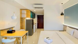 Een hotelkamer met een bed, een bureau met stoelen, een kitchenette en een deur naar een andere kamer.
