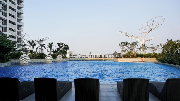 A swimming pool with lounge chairs and decorative elements. - Great Choice And Minimalist 2Br West Vista Apartment (Jakarta)