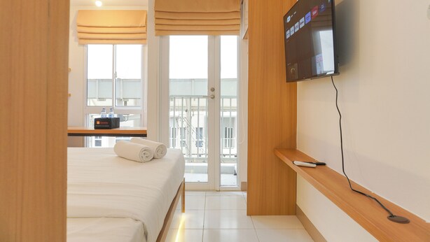 Ein Hotelzimmer mit Bett, einem an der Wand befestigten Fernseher, einem kleinen Tisch mit Fernbedienung und einem Fenster mit Blick nach draußen.
