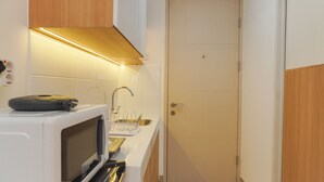 Eine kleine Küche mit Mikrowelle, Herd, Spüle und Holzschränken.