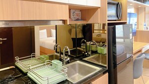 A compact kitchen with a refrigerator, sink, and dish drying rack.