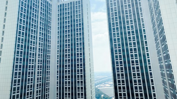 Two high-rise buildings with a clear view of the sky and distant landscape.