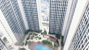 A high-rise building with multiple floors, a courtyard with a swimming pool, and a basketball court.