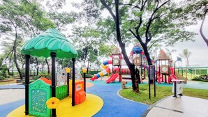 A playground with colorful play structures and a green-roofed shelter. - Comfy 3Br Sky House Bsd Apartment (Pagedangan)