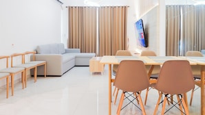 A modern living room with a sofa, chairs, a dining table, and a TV. - Comfy 3Br Sky House Bsd Apartment (Pagedangan)