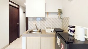 A compact kitchen with a sink, a small refrigerator, a microwave, and a coffee maker. - Modern 2Br At Mekarwangi Square Cibaduyut Apartment (Bandung)