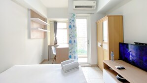 Hotellihuone, jossa on sänky, työpöytä, televisio ja ilmastointilaite.