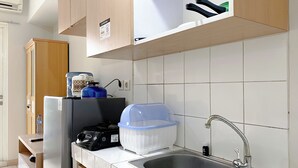 Kompakti keittiö, jossa on ruostumattomasta teräksestä valmistettu pesuallas, vedenkeitin, vesiautomaatti ja jääkaappi.