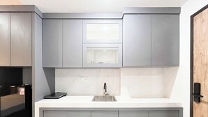 A modern kitchen with grey cabinets, a stainless steel sink, and a black countertop.