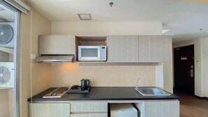 A compact kitchen with a microwave, kettle, and sink. - Modern And Spacious Studio Marina Ancol Apartment (Jakarta)