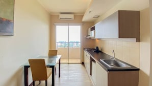 A compact kitchen with a dining area, a large window, and a view of the outdoors. - Modern And Spacious Studio Marina Ancol Apartment (Jakarta)