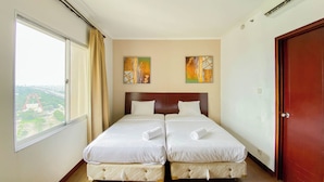 A hotel room with two beds, a large window with a view of a bridge, and two paintings on the wall. - Modern And Spacious Studio Marina Ancol Apartment (Jakarta)