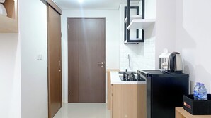 A compact kitchen with a sink, stove, and a coffee maker on a black countertop. - Restful And Well Designed Studio Transpark Juanda Bekasi Timur Apartment (Bekasi)