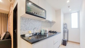 A modern kitchen with a black countertop, stainless steel sink, and a built-in range hood. - Modern Look And Cozy 1Br Branz Bsd City Apartment (Pagedangan)