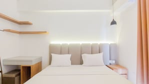 Quarto moderno com cama, mesas de cabeceira, escrivaninha e estantes embutidas.
