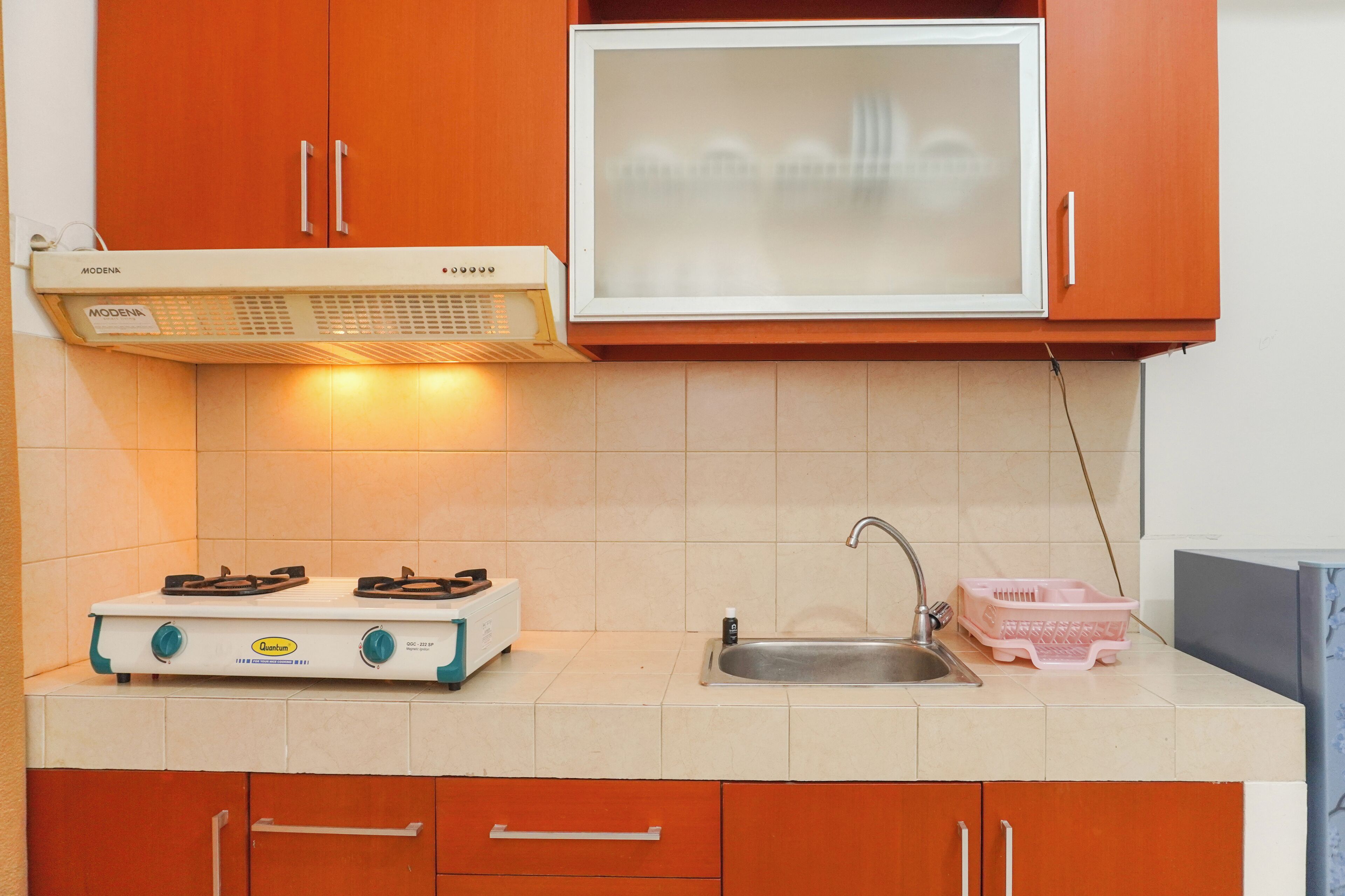A kitchen with a gas stove, sink, and orange cabinets.