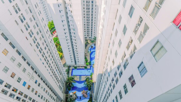 A high-rise building with multiple floors, a central courtyard with a swimming pool, and surrounding greenery.