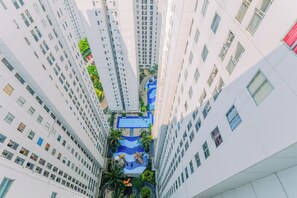 A high-rise building with multiple floors, a central courtyard with a swimming pool, and surrounding greenery. - Good Deal And Restful Studio Bassura City Apartment (Jakarta)
