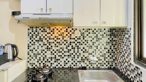 A kitchen with a black and white checkered backsplash, a stainless steel sink, and a gas stove. - Comfortable Stay Studio At Kebagusan City Apartment (Jakarta)