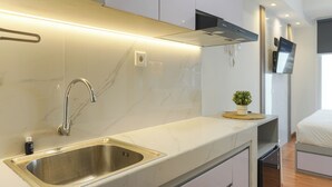A modern kitchen with a stainless steel sink, white marble backsplash, and a small potted plant on the countertop. - Compact Studio At Tokyo Riverside Apartment (Teluknaga)