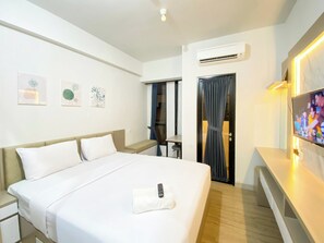 A hotel room with a bed, bedside tables, a TV, and artwork on the walls. - Good Choice And Homey Studio At The Alton Apartment (Semarang)