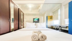Une chambre d’hôtel avec un lit, un téléviseur fixé au mur, un bureau et une armoire.