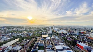 A cityscape with a river, residential buildings, and a prominent high-rise building. - Simply And Cozy Living Studio Vida View Makassar Apartment (Makassar)