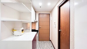 A narrow hallway with a white countertop, a white appliance, and a wooden door. - Simply And Cozy Living Studio Vida View Makassar Apartment (Makassar)