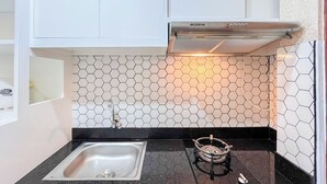 A kitchen with a stainless steel sink, a gas stove, and a hexagonal tile backsplash. - Simply And Cozy Living Studio Vida View Makassar Apartment (Makassar)