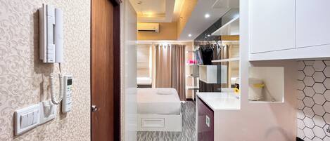 A hotel room with a bed, a bathroom, and a kitchenette.