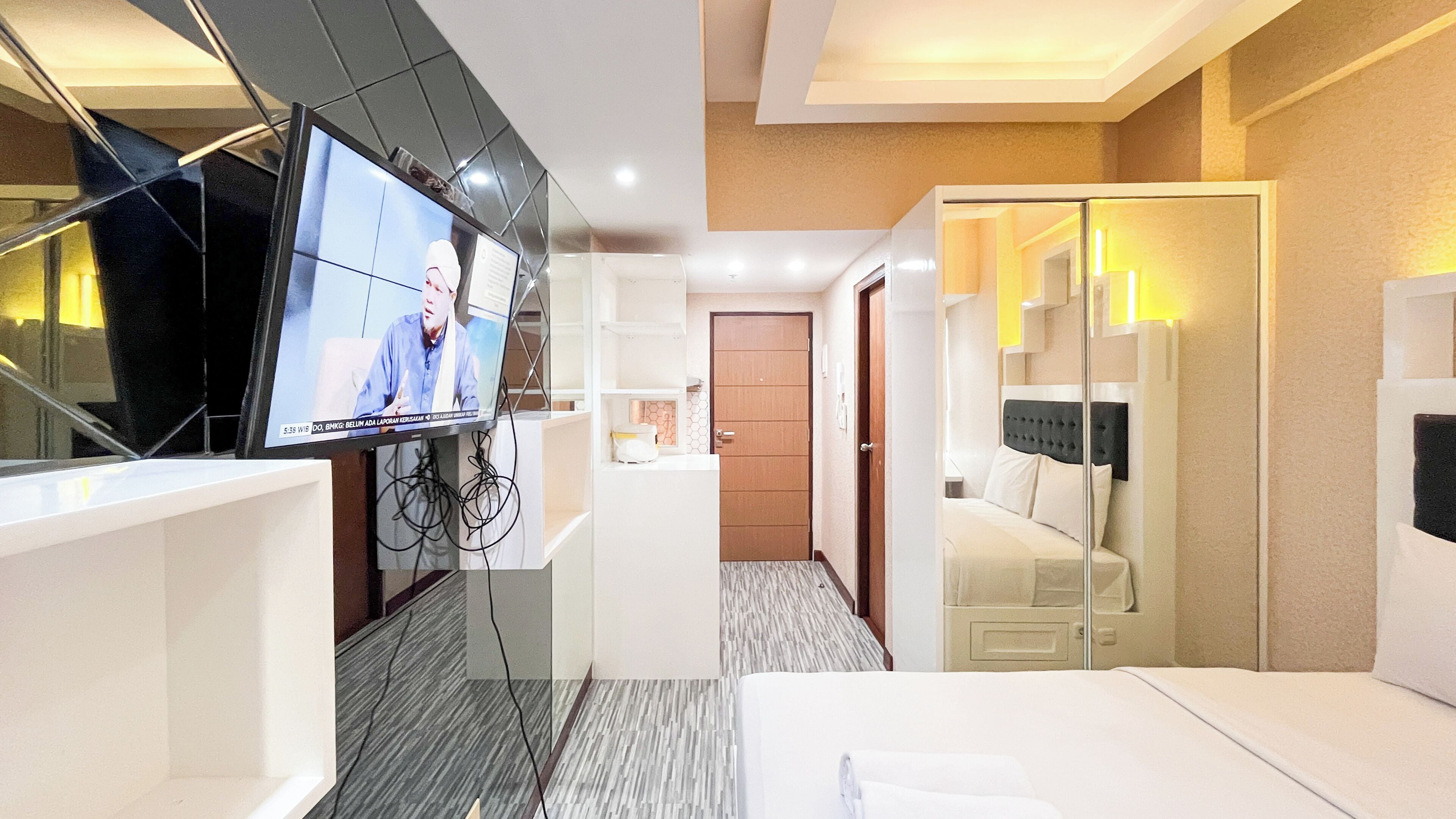 A hotel room with a TV, a bed, a wardrobe, and a bathroom.