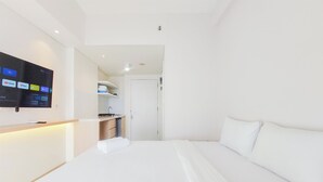 Une chambre d’hôtel équipée d’un lit, d’un téléviseur fixé au mur et d’un coin cuisine.