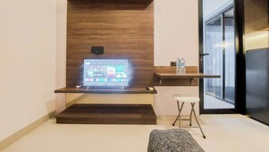 Une chambre moderne avec un téléviseur à écran plat fixé à un mur en bois, un petit tabouret et un banc.