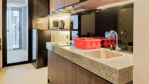 Une cuisine moderne dotée de plans de travail en granit, d’appareils électroménagers en acier inoxydable et d’un égouttoir à vaisselle rouge.