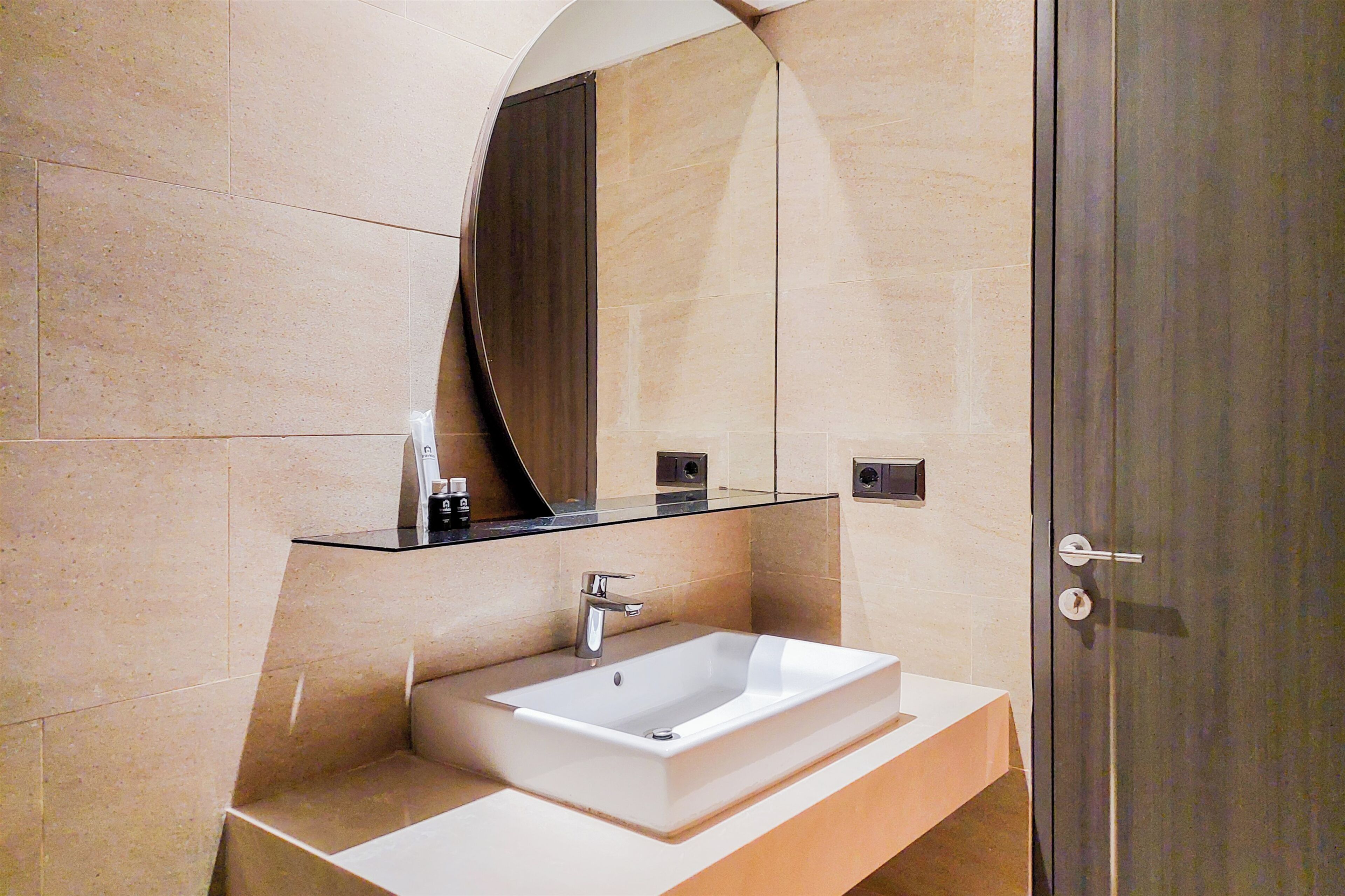A modern bathroom with a rectangular sink, a glass shelf above it, and a large mirror.
