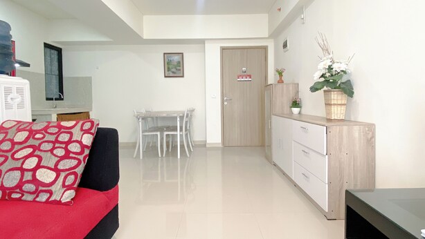 A modern, well-lit room with a sofa, a dining table, and a kitchenette area.