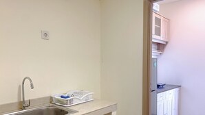 A kitchen with a stainless steel sink, a white countertop, and a cabinet with a microwave. - Comfortable Living 2Br At Meikarta Apartment (Cikarang)