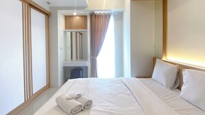 Ein modernes Hotelzimmer mit einem ordentlich bezogenen Bett, einem kleinen Schreibtisch und einem Spiegel darüber.